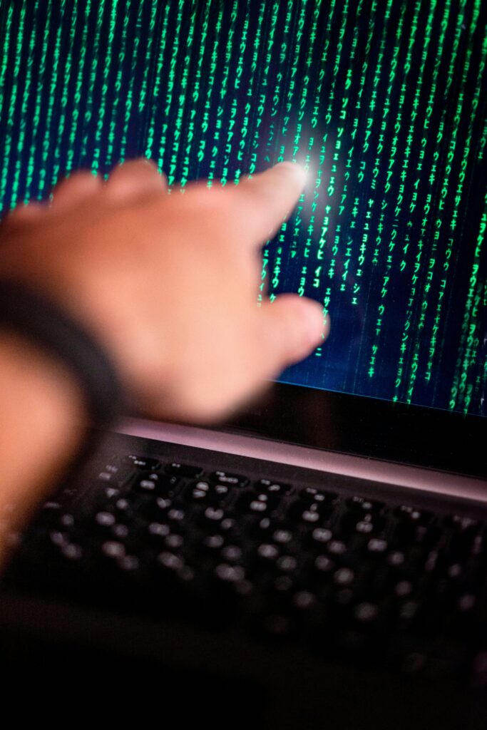 pexels-photo-7444597-7444597 A person points at a glowing code on a computer screen, symbolizing technology interaction.